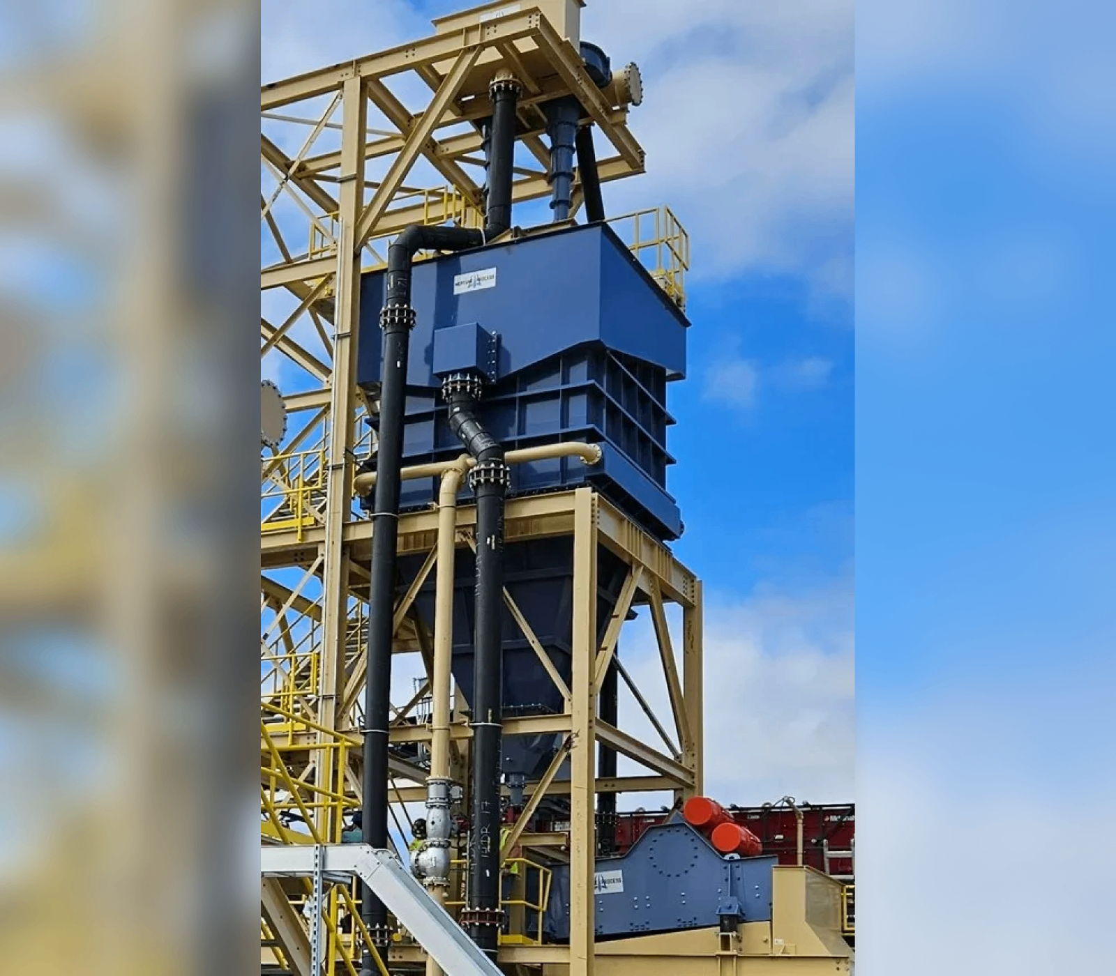 A large blue machine is on top of a yellow structure.