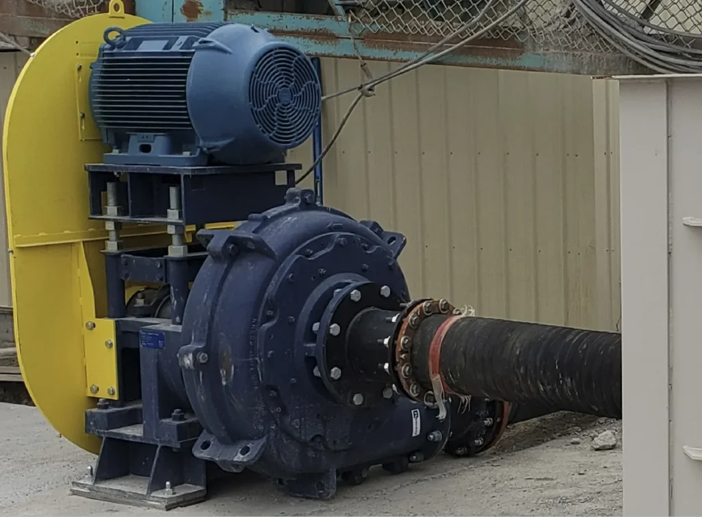 A large blue pump sitting next to a pipe.