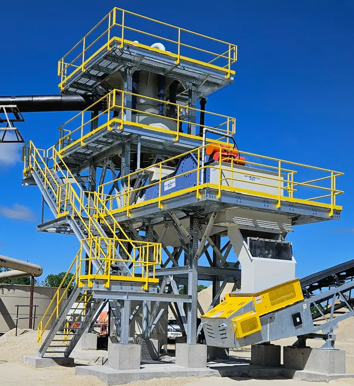 A large yellow and gray machine on top of a cement pile.